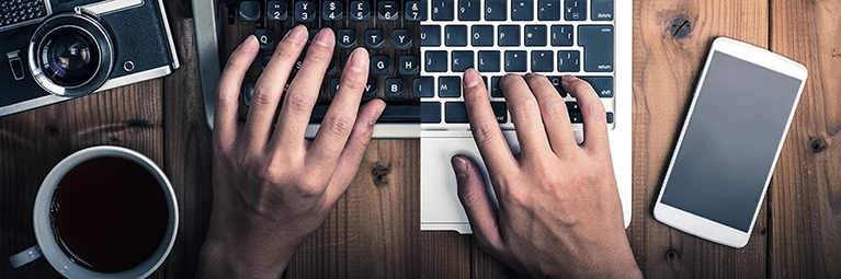 A photo of one hand typing on a laptop keyboard, while the other types on a typewriter to symbolize digital transformation.