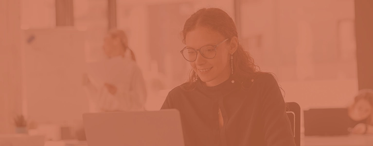 A photo of a smiling businesswoman looking at a computer screen while looking for career coaching services.